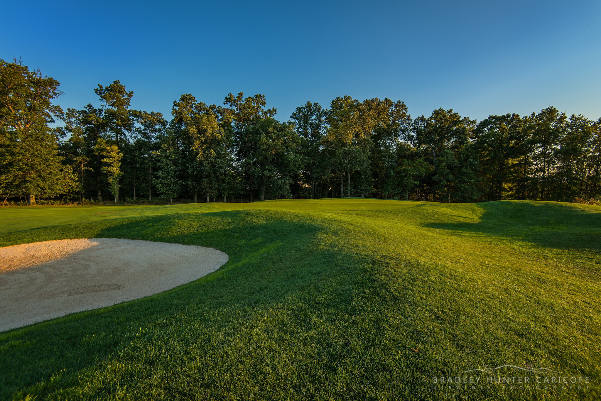 golf course with bunker and trees